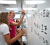 Sophomores work out math problems on the whiteboard