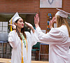 Students high five on caps and gowns on Graduation Day