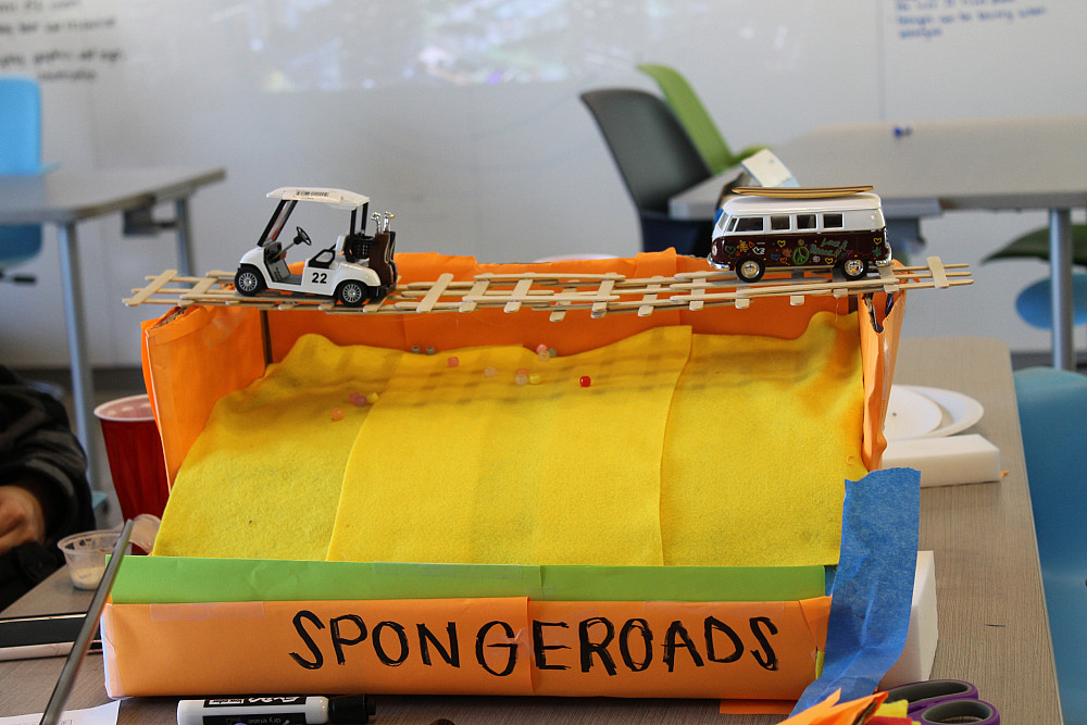 The SpongeRoads team orchestrates their final product using a model made of paper, cardboard, and...