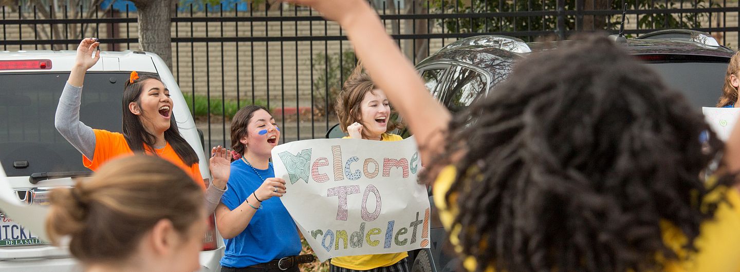 Students holding welcome signs and cheering