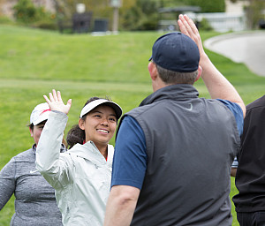 A student golfer high fives an adult participant at the 2019 Cougar Classic