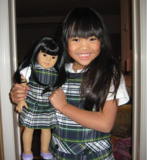 Lauren wearing her St. Isadore's uniform in elementary school hugging an American Girl Doll. Her ...