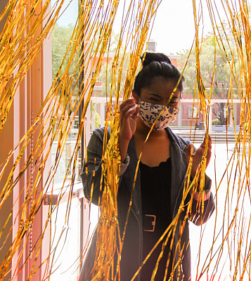 Angelica Medina walks through gold streamers, entering the Jean Hofmann Center for Innovation.