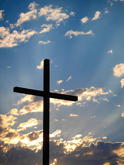 A cross silhouetted by morning sky