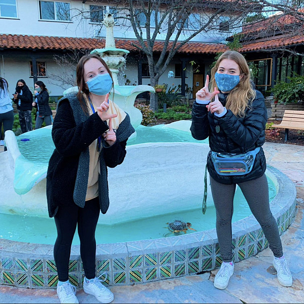 Mollie Smith and another student pose in front of the fountain during a Journey retreat