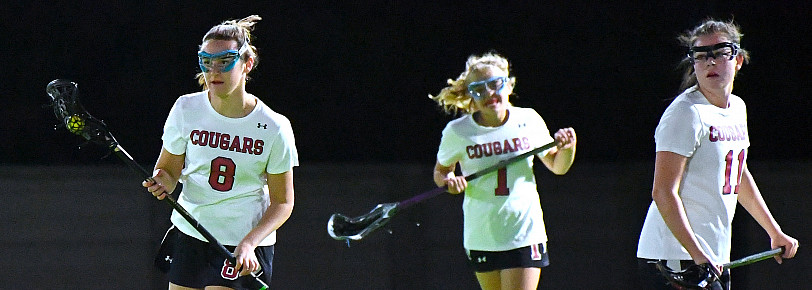 3 Lacrosse athletes play in the night